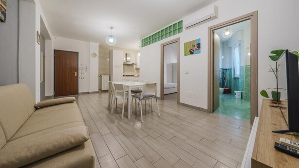 Una sala de estar moderna con un sofá, mesa de comedor, sillas y televisión.