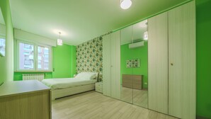 Una habitación con cama, armario, radiador y ventana.