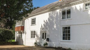 A white building with a sign reading 'Rectory Cottage,' a brick chimney, and a gravel driveway. - Rectory Cottage (Alton)