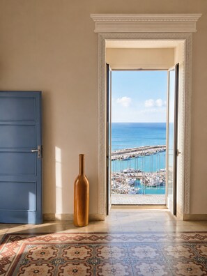 An open door leading to a balcony with a view of the sea and a marina. - Belvedere & Blu - Panorama 180° - Breathtaking Ocean View (Sciacca)