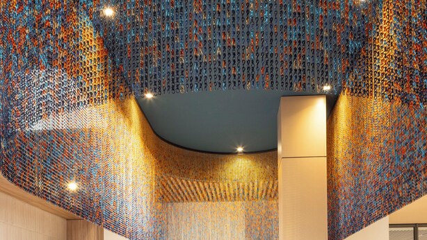 A chef preparing food in a modern kitchen with a unique ceiling design. - Parkest Hôtel & Spa (Genas)
