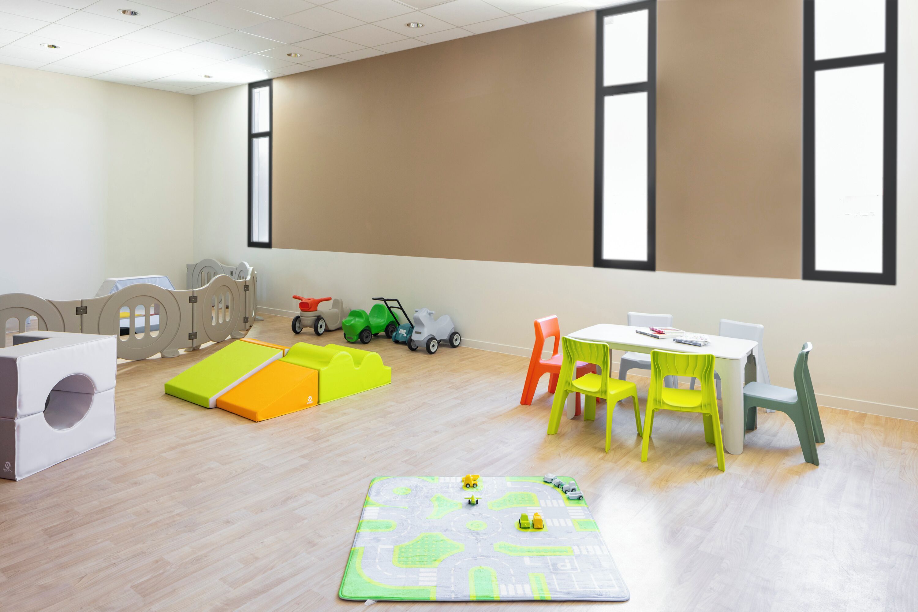 A children's play area with a mat, play structures, and a table with chairs.