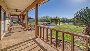 Un porche cubierto con vistas a una zona verde, un banco de madera y una mesa de patio.