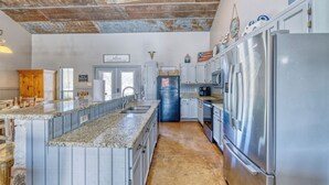 Una cocina con encimeras de granito, electrodomésticos de acero inoxidable y un techo rústico.