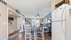 A kitchen with a dining table, chairs, a refrigerator, and a ceiling fan. - Sea Cabin Shores w Pool View and Ocean Peek (North Myrtle Beach)