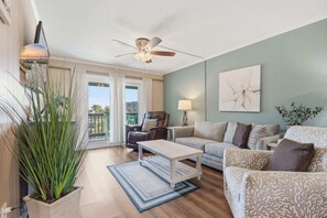 Un salon comprenant un canapé, un fauteuil, une table basse et une plante en pot.