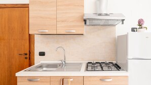 A modern kitchen with a stainless steel sink, a gas stove, wooden cabinets, and a white countertop. - Apartment 'Lu Marchese' with Private Terrace, Wi-Fi and Air Conditioning (Minervino di Lecce)