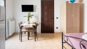 A room with a bed, a table with chairs, a television, a wardrobe, and a door. - Apartment 'Lu Marchese' with Private Terrace, Wi-Fi and Air Conditioning (Minervino di Lecce)