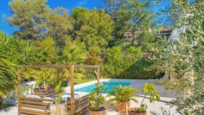Ein Poolbereich mit einer Holzpergola, Topfpflanzen und Blick auf einen Hügelhang.