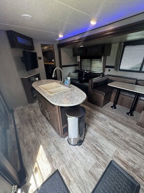 Cocina compacta para autocaravana con fregadero, cocina y zona de estar.
