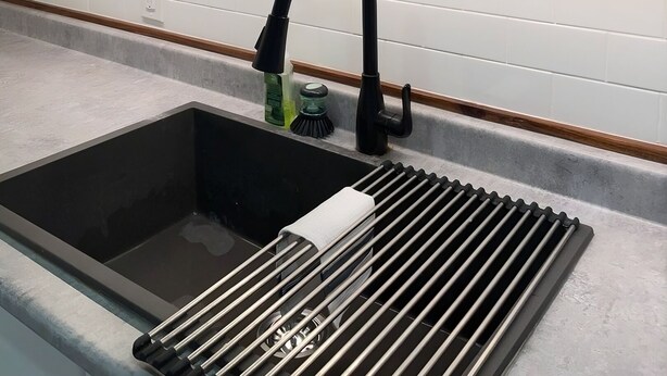 A kitchen with a black faucet, a sink with a metal strainer, and a shelf with black plates. - Cozy Albert St Retreat (Waterloo)