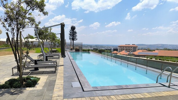 A swimming pool with lounge chairs and a view of distant buildings.