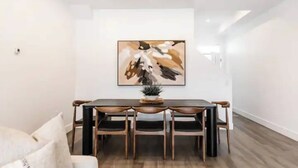 A dining area with a rectangular table, six chairs, and a large abstract painting on the wall. - Luxury 4-bed, 3.5-bath home in Shelter Bay, West K,  rooftop deck with hot tub. (West Kelowna)
