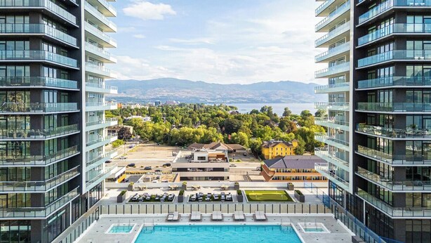 A high-rise hotel with a rooftop pool and a view of a cityscape and mountains. - Skyfall 3 Bed 1 Den Lakeview Amenity Rich 30 Floor (Kelowna)