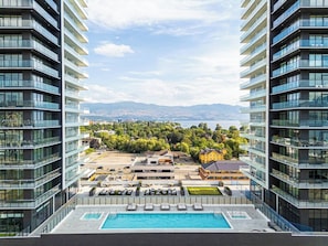 Ein Hochhaus mit Pool auf dem Dach und Blick auf Stadt und Berge.