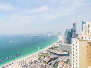 Un paisaje urbano costero con rascacielos, una playa y un muelle.