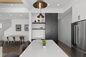 Une cuisine moderne dotée d’un îlot central, d’appareils électroménagers intégrés et d’un coin repas avec un escalier.