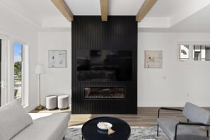 Un salon moderne avec une cheminée, un canapé, une table basse et des œuvres d’art accrochées aux murs.
