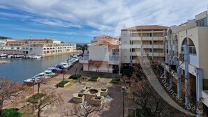 Un port de plaisance avec des bateaux, un immeuble doté de balcons et un ciel dégagé.