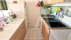 Une cuisine de taille réduite, équipée d’un lave-linge, d’un évier et d’un petit plan de travail.
