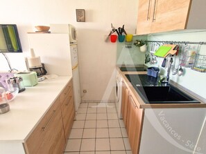 A compact kitchen with a washing machine, a sink, and a small countertop. - 111 / T2 PROCHE MER AVEC LOGGIA (Sète)