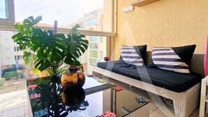 Un balcon agrémenté d’un canapé en osier, d’une plante en pot et d’un vase décoratif.
