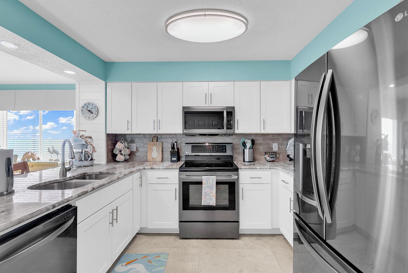 A modern kitchen with white cabinets, stainless steel appliances, a microwave, oven, and refrigerator.