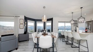 Une cuisine moderne avec un coin bar, de grandes fenêtres et un espace repas offrant une vue agréable.