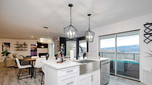 Une cuisine moderne dotée d’un grand îlot central, de luminaires suspendus et offrant une vue sur la ville.