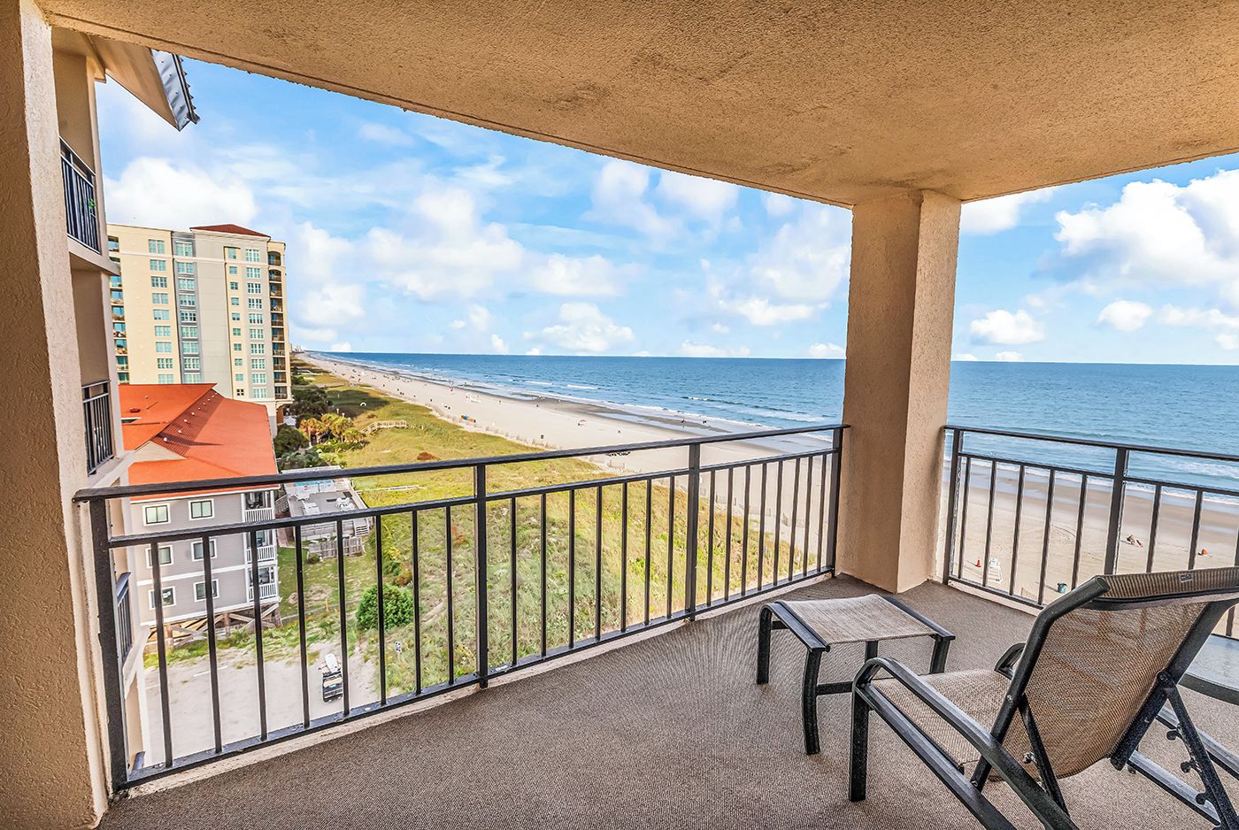 A balcony with a view of a beach and a building.