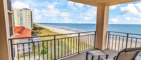 A balcony with a view of a beach and a building.