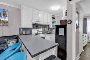 Eine moderne Küche mit weißen Schränken, einem schwarzen Kühlschrank und einer grauen Arbeitsplatte.
