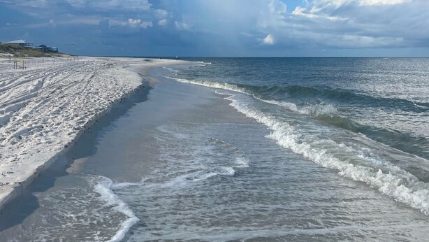 En strand med en sandstrand och vågor.