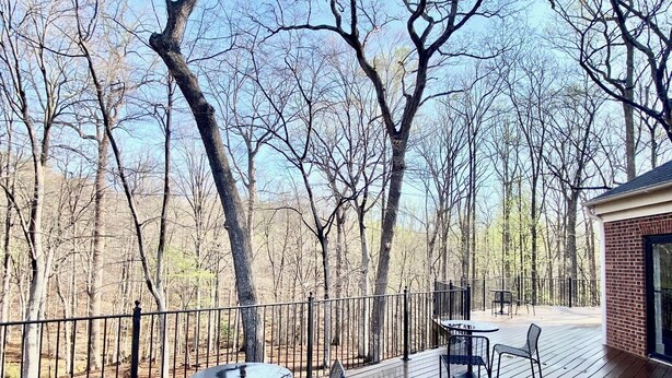 A wooden deck with outdoor seating, surrounded by trees.
