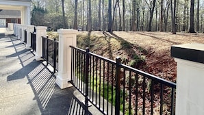 A building with a covered walkway and a forested area in the background.