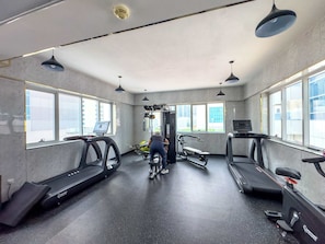 A gym with treadmills, a weight machine, and a person using a bike. - StayShort - Chic 1BR in Dubai Marina Sleeps 2 (Dubai Marina)