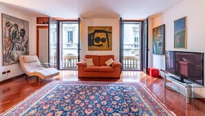A living room with a sofa, a TV, a large rug, and artwork on the walls. - Appartamento Magnifico - Porta Venezia  (Milan)