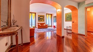 A spacious hallway with wooden flooring, a large mirror, and a sofa in the background. - Appartamento Magnifico - Porta Venezia  (Milan)
