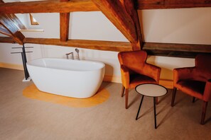 A modern bathroom with a freestanding bathtub, two velvet armchairs, and a small round table. - Die Burg - Kurfürstlich Flämisch (Bad Belzig)
