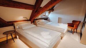 A bedroom with two beds, a small table, a chair, and a radiator. - Die Burg (Bad Belzig)