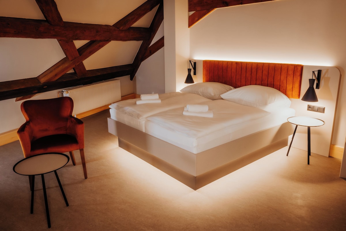 A modern hotel room with a large bed, a red chair, and two bedside tables.