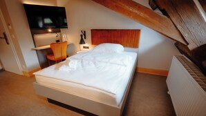 A bedroom with a bed, a desk, a chair, a television, and a radiator. - Die Burg (Bad Belzig)