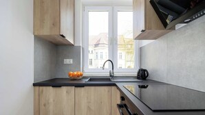 Eine moderne Küche mit Holzausstattung, einer schwarzen Arbeitsplatte und einem Fenster mit Blick auf Gebäude.