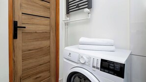 Ein moderner Waschraum mit einer Waschmaschine mit Frontlader, einer Holztür und einem Handtuchhalter.