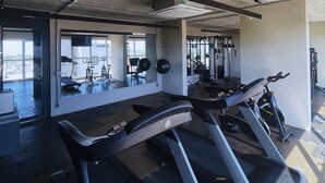 Een fitnessruimte met loopbanden, elastiekjes en krachttrainingsapparaten.