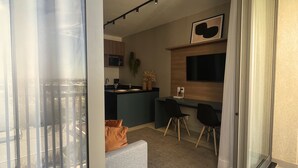 Een moderne keuken met een bar, een eettafel met stoelen en een grote televisie aan de muur.