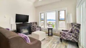 Ein Wohnzimmer mit Kamin, Fernseher und Blick ins Freie.