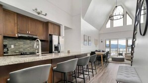 Eine moderne Küche mit Barbereich, Holzschränken und einem großen Fenster mit Blick auf eine reizvolle Landschaft.