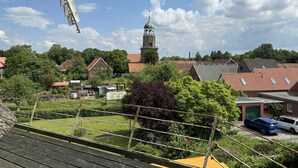 Ett bostadsområde med hus, en kyrka med ett torn och vindkraftverk i bakgrunden.