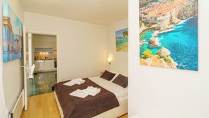 Ein Schlafzimmer mit Bett, einem Meeresblick-Gemälde, einer Küchenzeile und einem Badezimmer.